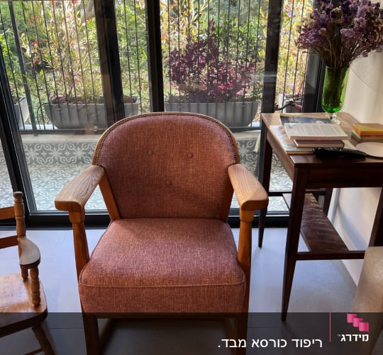 כורסה מרופדת בבד חום עם ידיות עץ